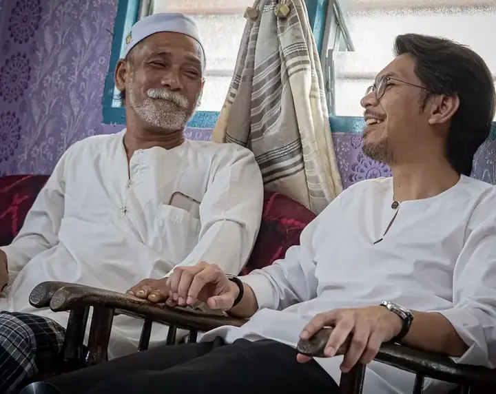 Kamil Munim berbual bersama seorang warga emas di ruang tamu rumah penduduk